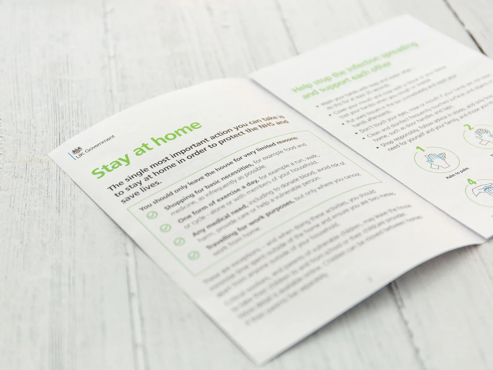 An open printed booklet with green headings and illustrations on a white wooden table