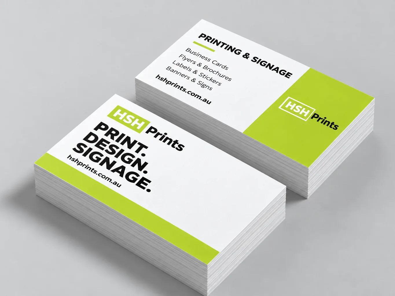 Mockup of two stacks of HSH business cards, the white front reading Print. Design. Signage. and the lime-panelled back listing the services