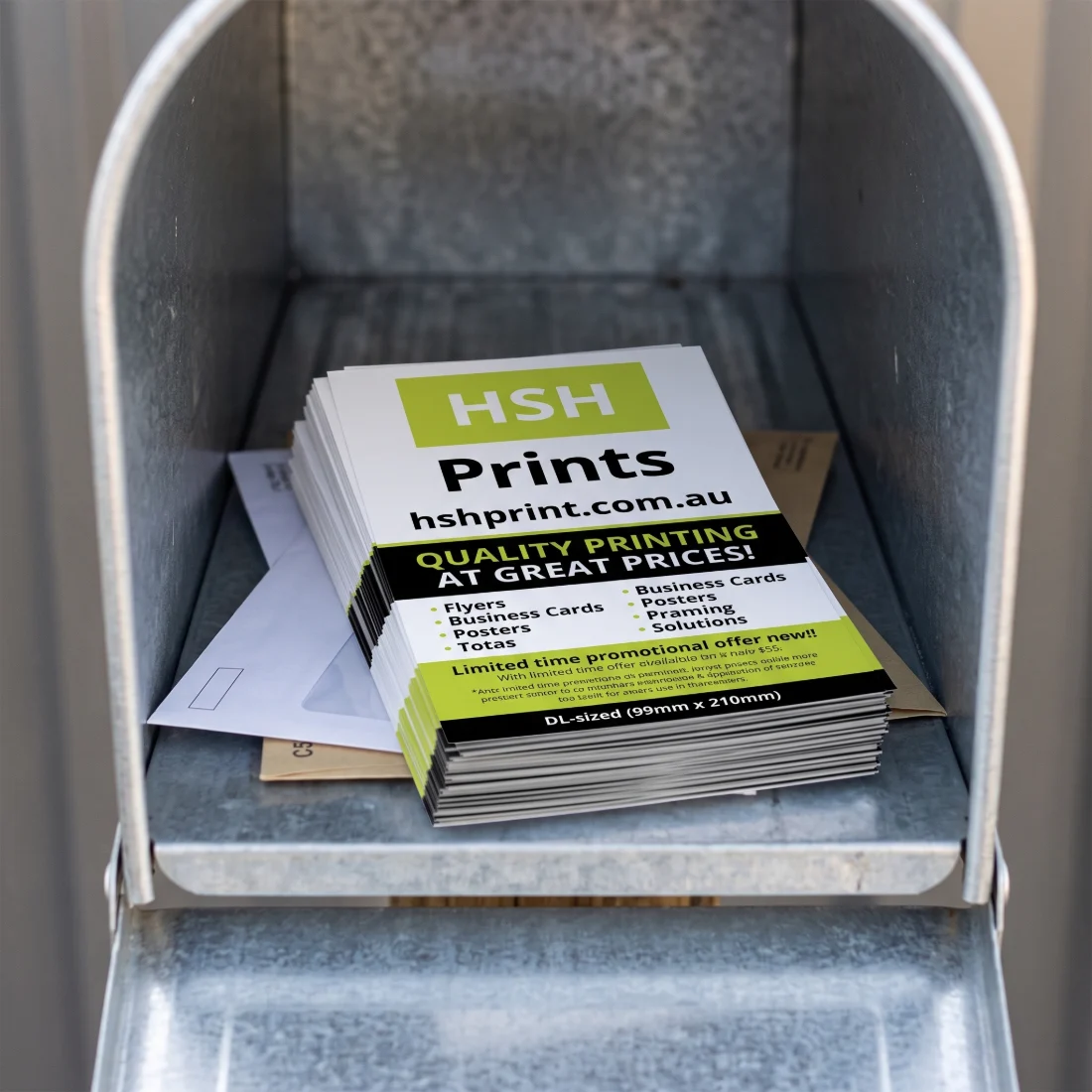 A stack of DL flyers sitting in an open galvanised letterbox alongside two envelopes