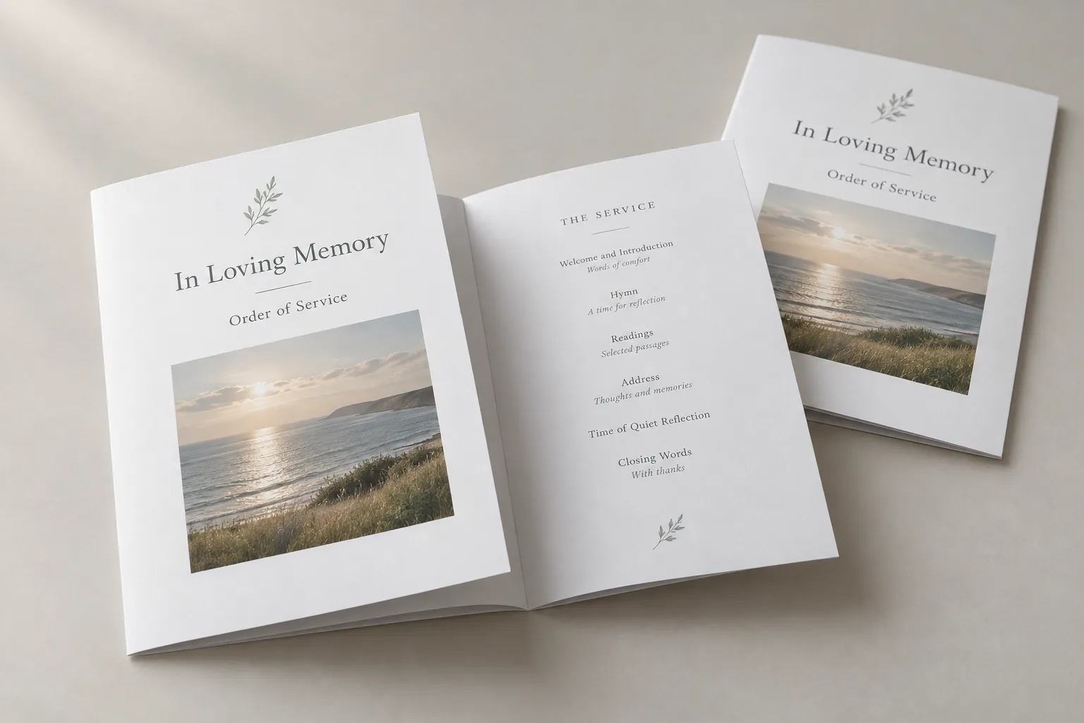 Two A5 folded orders of service headed In Loving Memory with a coastal photograph on the cover, one open to the order of the service