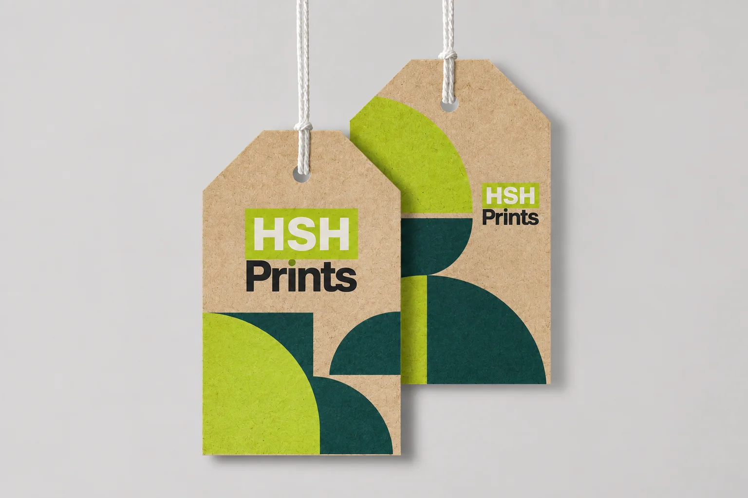 Two cut-corner banner swing tags on kraft card, printed with the HSH Prints logo and green half-circle shapes, hung on white string
